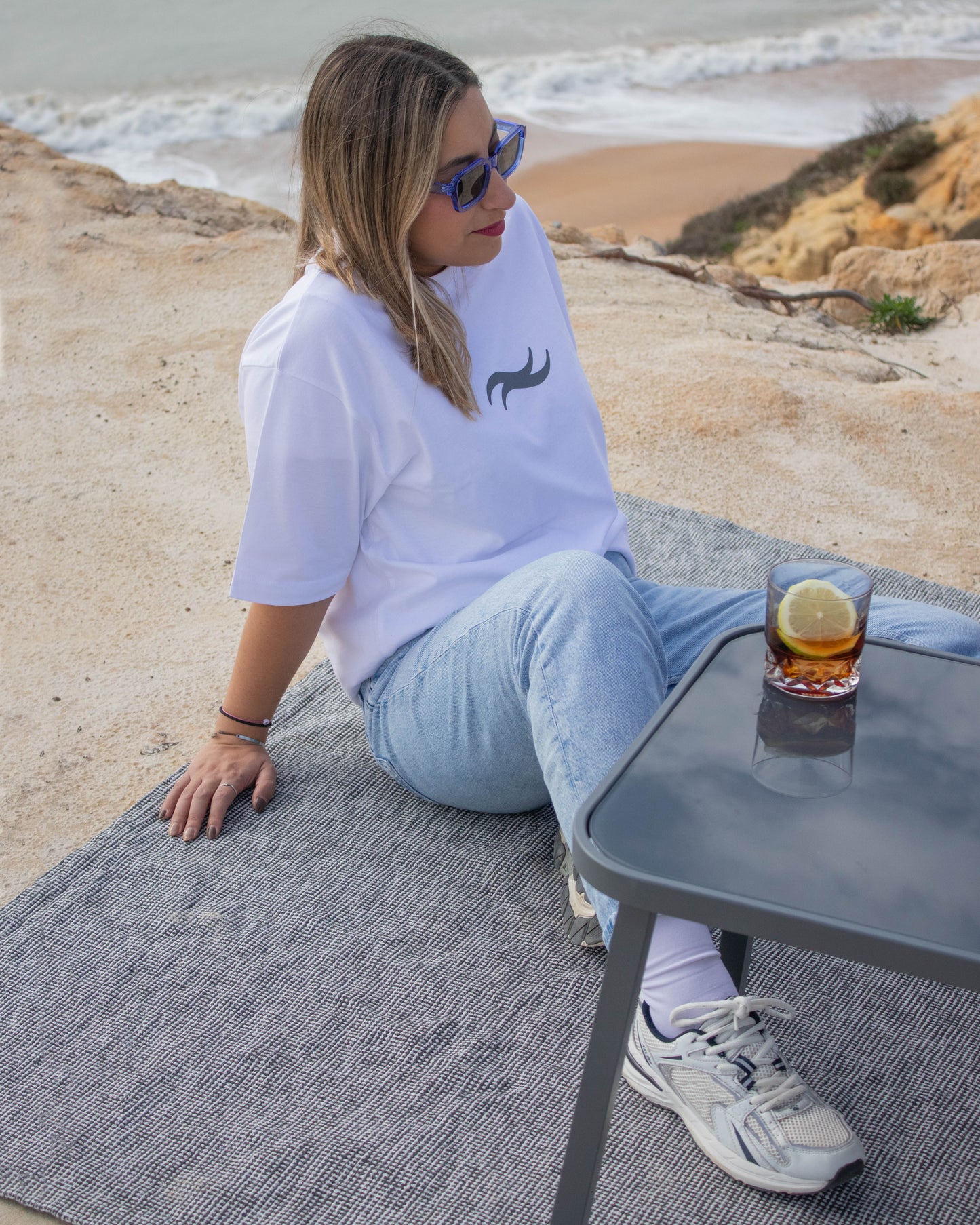 Camiseta blanca básica de la colección con logotipo de las olas, siendo usada por modelo en el mar de Huelva, en Mazagón